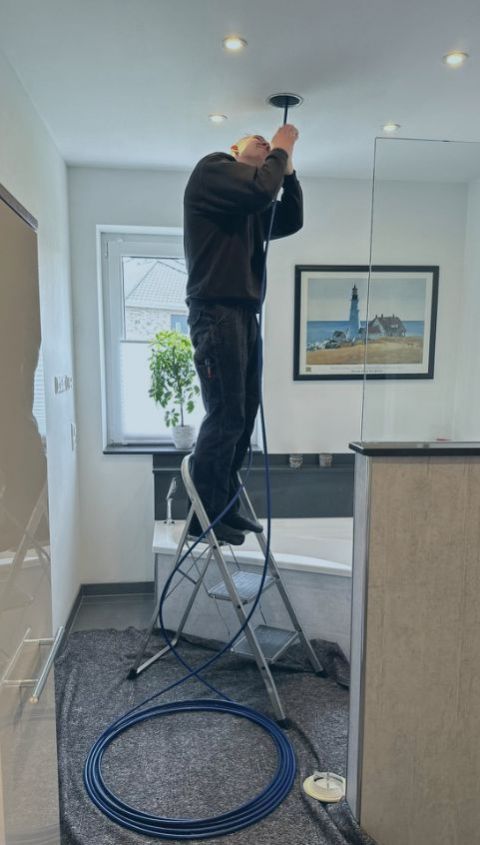 Techniker reinigt Lüftungskanal an der Decke mit rotierender Bürste